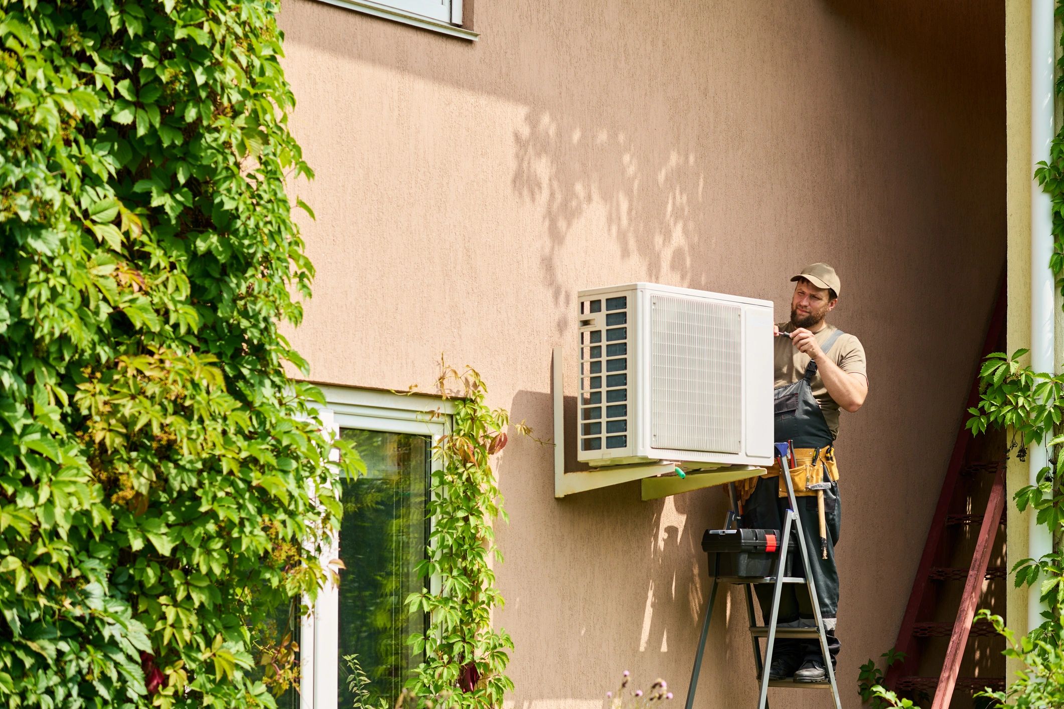 HVAC technician servicing an outdoor air conditioning unit at a home