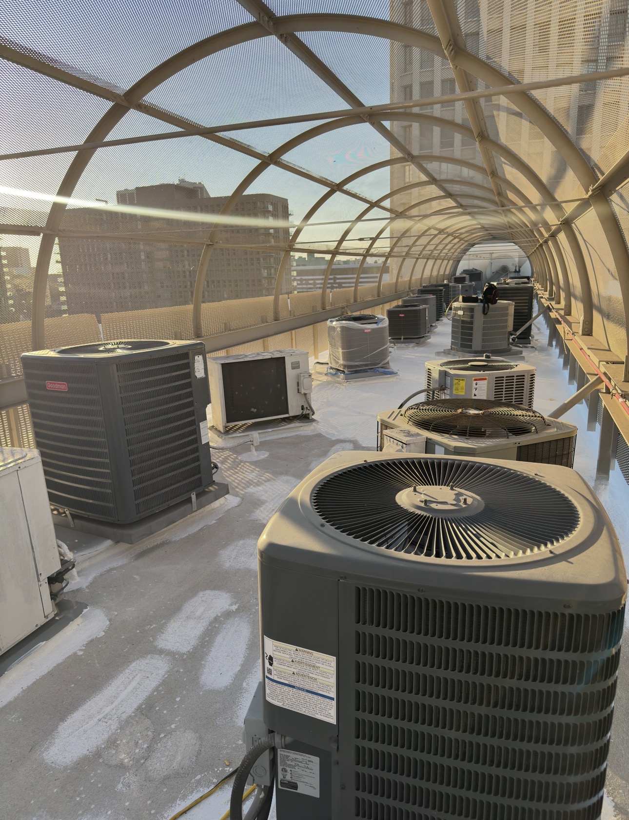 Multiple outdoor HVAC condenser units installed along a rooftop walkway